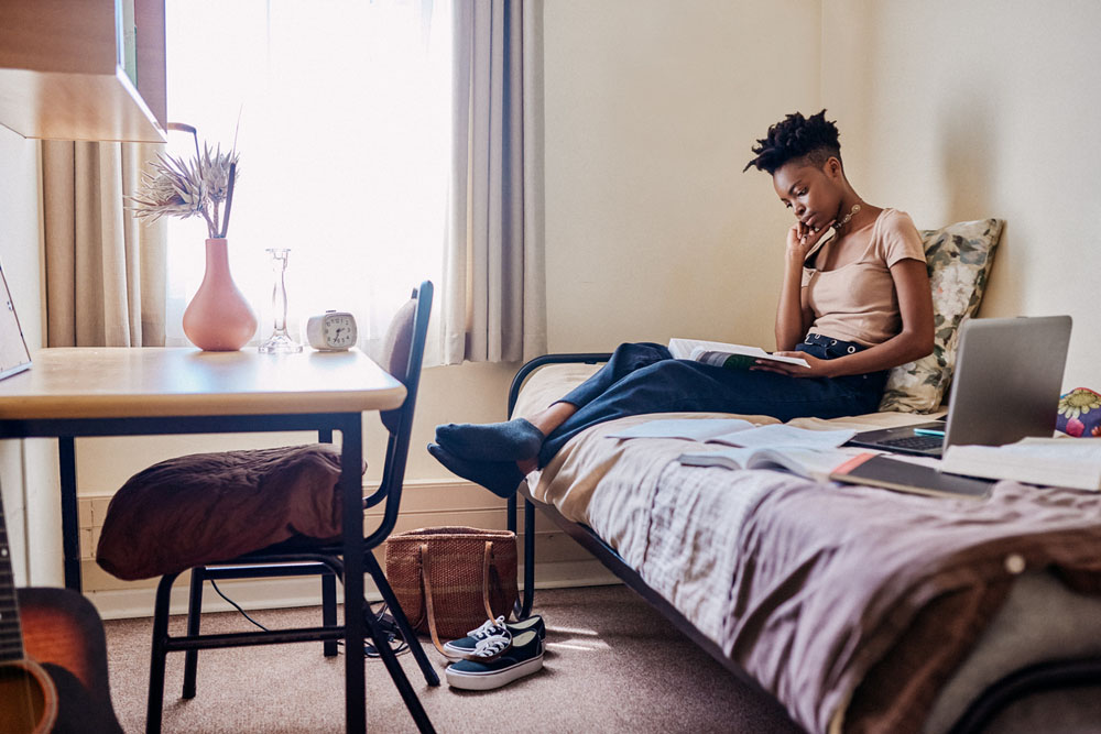 A young adult with ADHD studying in a dorm room while managing independent living responsibilities