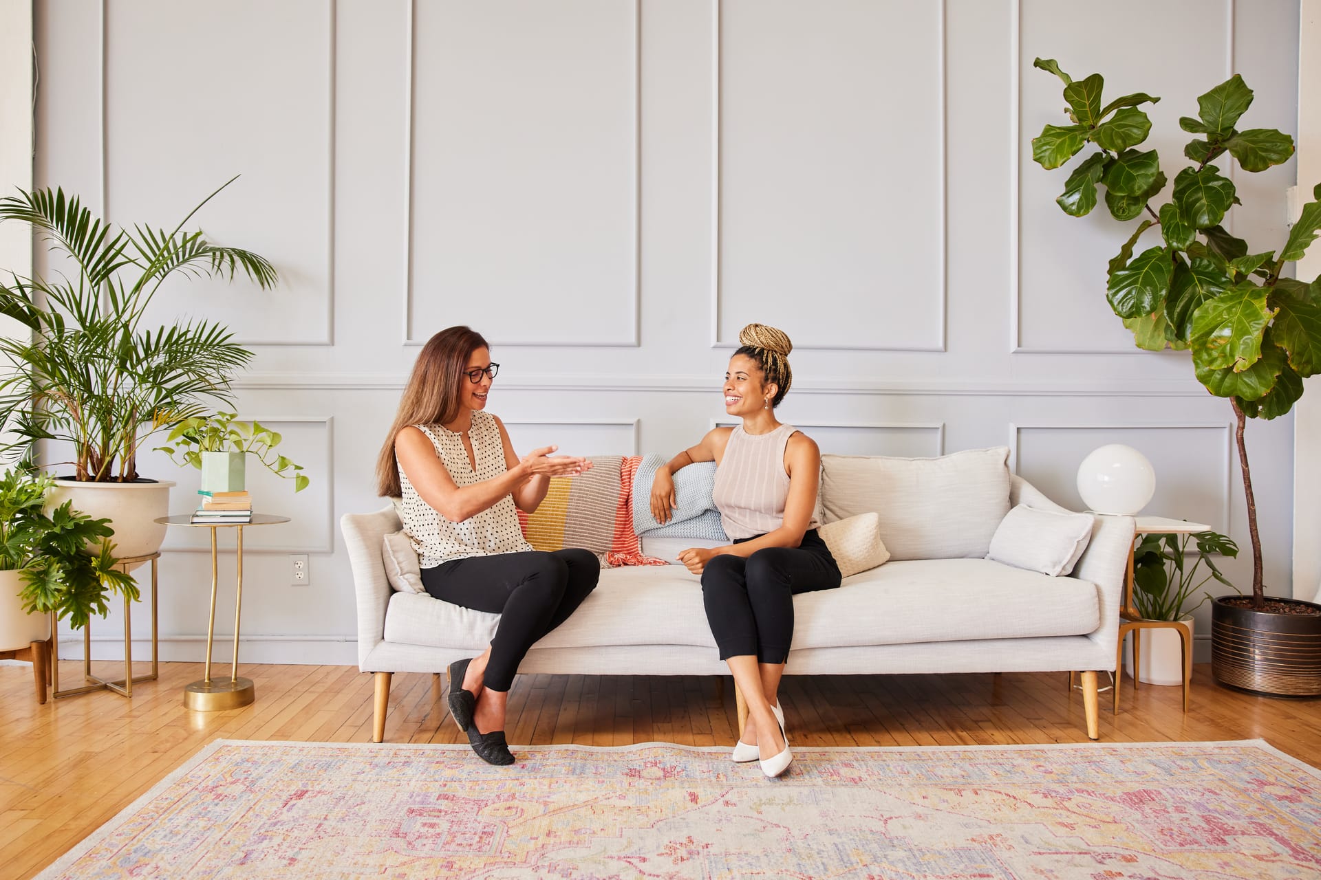 Two women laughing together on a sofa, representing supportive ADHD care