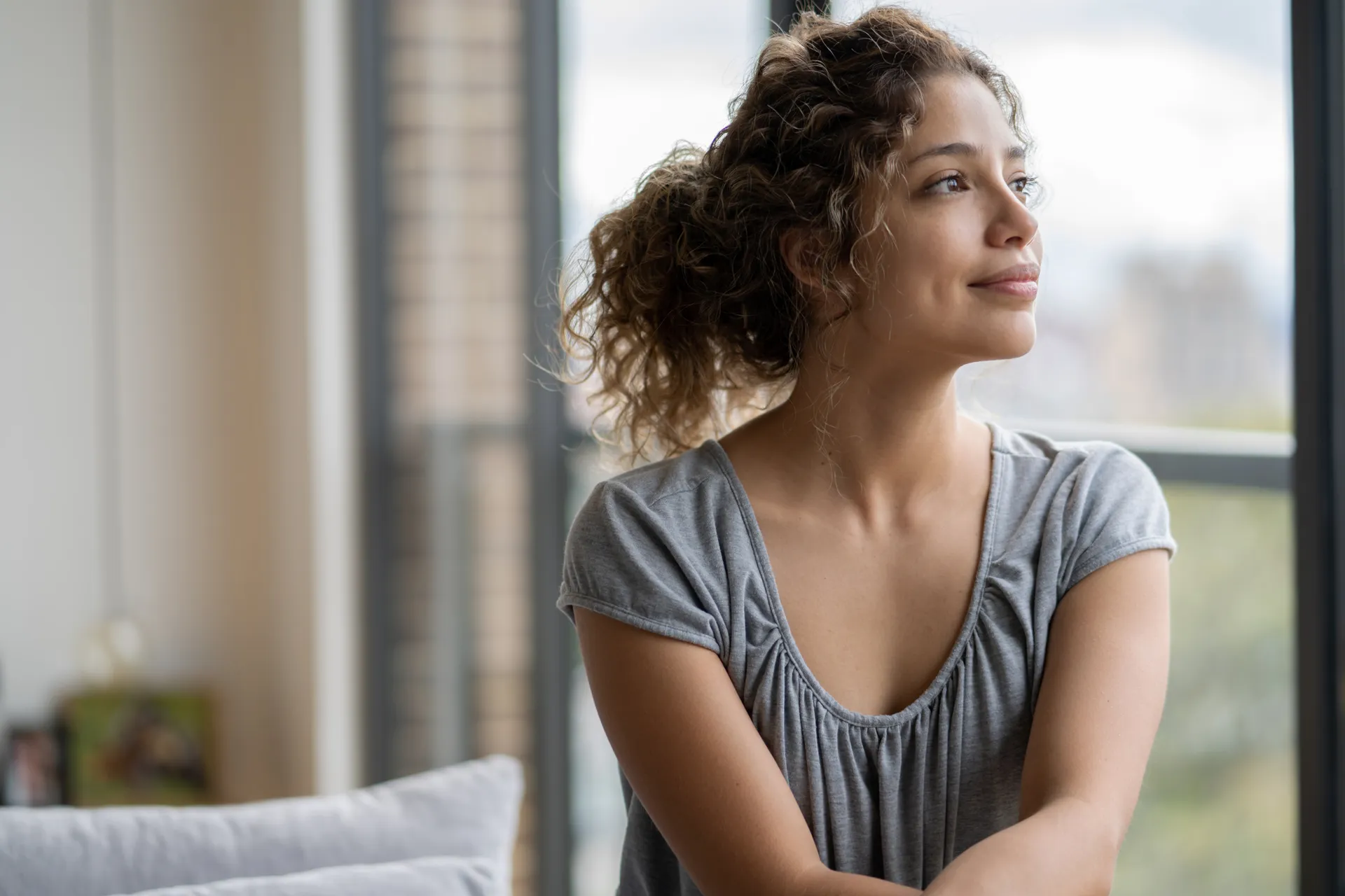 Woman at home looking thoughtfully toward a window — a calm moment of clarity after a virtual ADHD diagnosis.